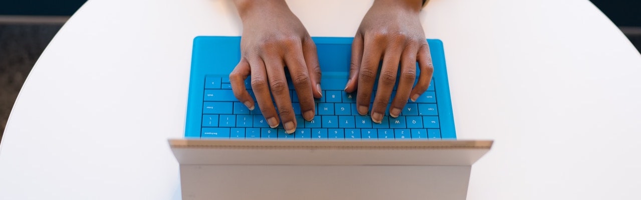A student's hands type a personal statement on a blue laptop.